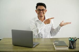 young asian businessman in a workplace holding copyspace imaginary on the palm to insert an ad, wearing white shirt with glasses isolated photo