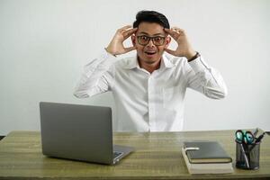 young asian businessman in a workplace with surprise expression, wear white shirt with glasses isolated photo