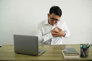 young asian businessman in a workplace having a pain in the heart, wearing white shirt with glasses isolated photo