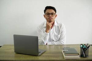 young asian businessman in a workplace looking front thinking wear white shirt with glasses isolated photo