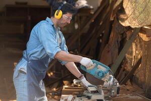 Portrait of a craftsman working with a circular saw at a wood workshop photo