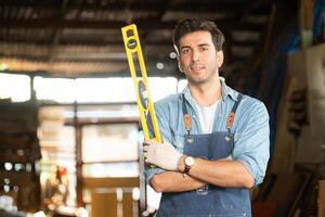 Portrait of a carpenter holding a spirit level in his workshop. photo