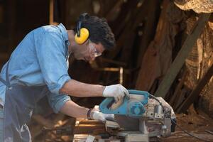 Portrait of a craftsman working with a circular saw at a wood workshop photo