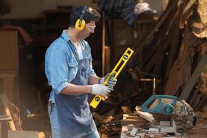 Portrait of a carpenter holding a spirit level in his workshop. photo