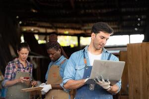 Portrait of carpenter male worker standing with laptop in workshop photo