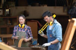 Carpenter and his assistant working together in a carpentry workshop photo