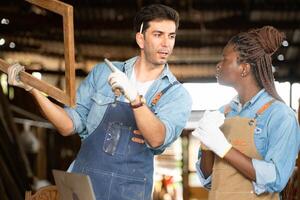 Carpenter and his assistant working together in a carpentry workshop photo