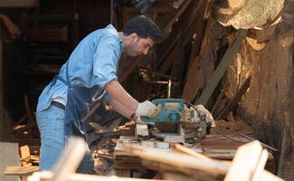 Portrait of a craftsman working with a circular saw at a wood workshop photo