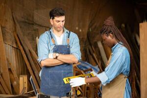 Carpenter and his assistant working together in a carpentry workshop photo