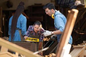 Carpenter and his assistant working together in a carpentry workshop photo