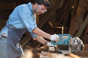 Portrait of a craftsman working with a circular saw at a wood workshop photo