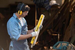 Portrait of a carpenter holding a spirit level in his workshop. photo