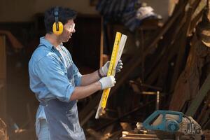 Portrait of a carpenter holding a spirit level in his workshop. photo