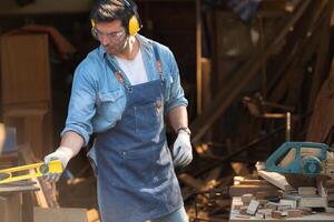 Portrait of a carpenter holding a spirit level in his workshop. photo