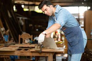 Carpenter working on laptop in his workshop at a woodworking factory photo