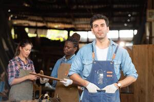 Portrait of carpenter male worker standing in front of colleague in workshop photo
