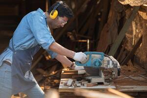 Portrait of a craftsman working with a circular saw at a wood workshop photo