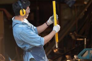 Portrait of a carpenter holding a spirit level in his workshop. photo