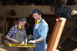 Carpenter and his assistant working together in a carpentry workshop photo