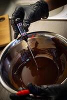 Woman cooking tasty melted chocolate on table in kitchen. photo