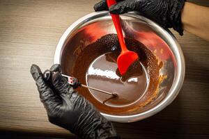 Woman cooking tasty melted chocolate on table in kitchen. photo