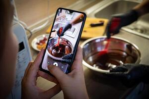 mujer Cocinando sabroso Derretido chocolate en mesa en cocina. foto