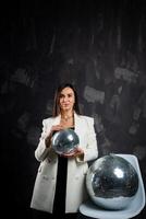 Portrait of a woman holding a silver disco ball. Taken in a photo studio.