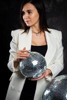 Portrait of a woman holding a silver disco ball. Taken in a photo studio.