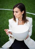 A business woman with a large cup, sitting on a green lawn in the park. photo