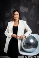 Portrait of a woman holding a silver disco ball. Taken in a photo studio.