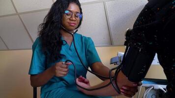 professionnel africain américain femelle médecin séance à hôpital et mesure du sang pression de une patient. soins de santé et la prévention concept video