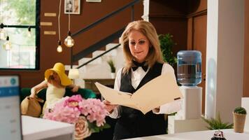 Staff working with reservations forms, checking accommodation room booking at hotel front desk. Woman receptionist preparing to welcome guests at luxury tropical summer resort. photo