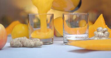 Pumpkin and ginger smoothie is poured into glasses against a background of fresh vegetables and fruits. The fresh cocktail is ready to eat. Healthy and vegetarian food concept. Ultra 4K Close-up video