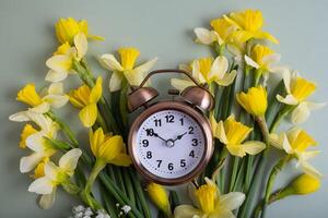 Alarm clock with spring flowers top view. Spring time, daylight savings concept, spring forward photo