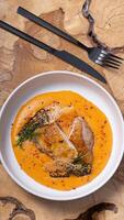 A plate with fried chicken and carrot and potato puree with black cutlery on wooden table photo