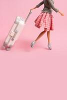 The doll carries a luggage on wheels. Travel, vacation creative minimalistic concept. Copy space. photo