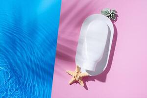 Mock up white plastic cream bottle on podium flat lay on pink background with blue water waves. Hot summer scene. photo