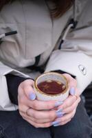 Cup with mulled wine in female hands, angle view photo