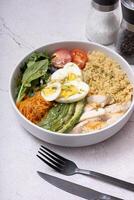 A bowl of couscous, meat, eggs and vegetables angle view on grey background. photo