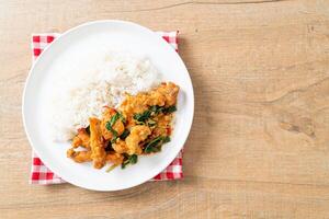 stir-fried fried fish with basil and chili in thai style topped on rice photo