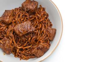 Jjapaguri o chapaguri, frijoles negros coreanos fideos picantes con carne de res sobre fondo blanco. foto