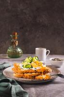 Toasts with cream cheese, cucumber, poached egg and sesame seeds on a plate vertical view photo