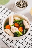 Diet soup with chicken fillet and boiled vegetables in a bowl on the table vertical view photo