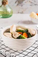 Homemade soup with chicken, cauliflower, broccoli, carrots and green beans in a bowl vertical view photo
