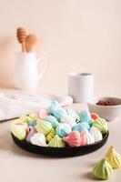 Multi-colored mini meringues on a plate on the table vertical view photo