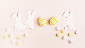 White decorative bunnies, Easter eggs and meringues on a pink background top view web banner photo