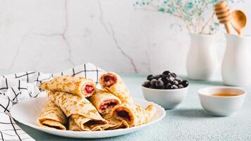 Homemade pancake rolls with berry filling on a plate on the table web banner photo