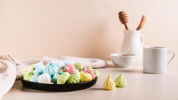 Multi-colored mini meringues on a plate on the table web banner photo