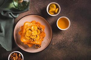 Toasts with caramelized banana, honey and walnuts for breakfast on the table top view photo