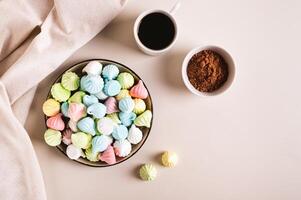 Multi-colored mini meringues on a plate on the table top view photo